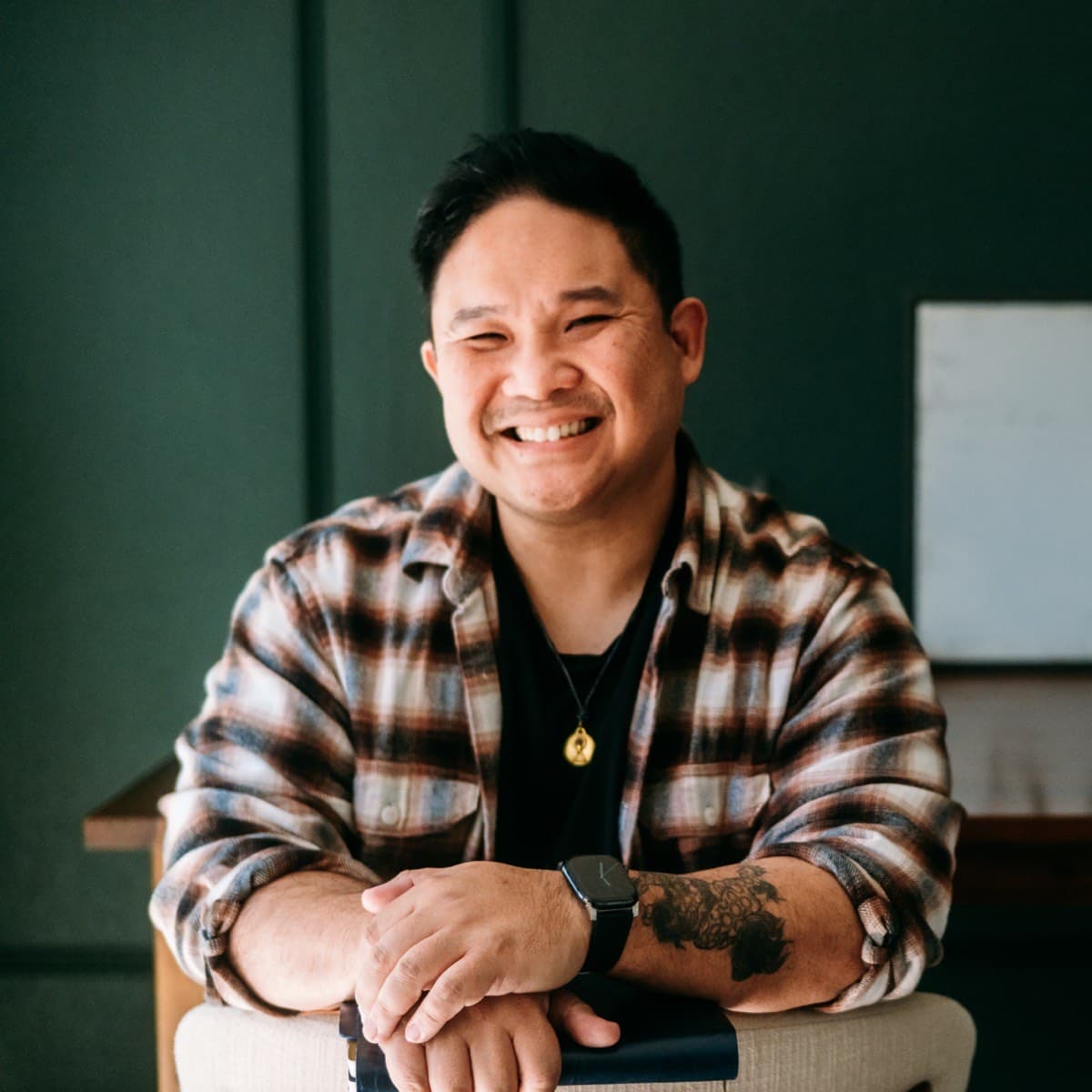 Anthony Lê, in a plaid shirt, looking warmly at the camera