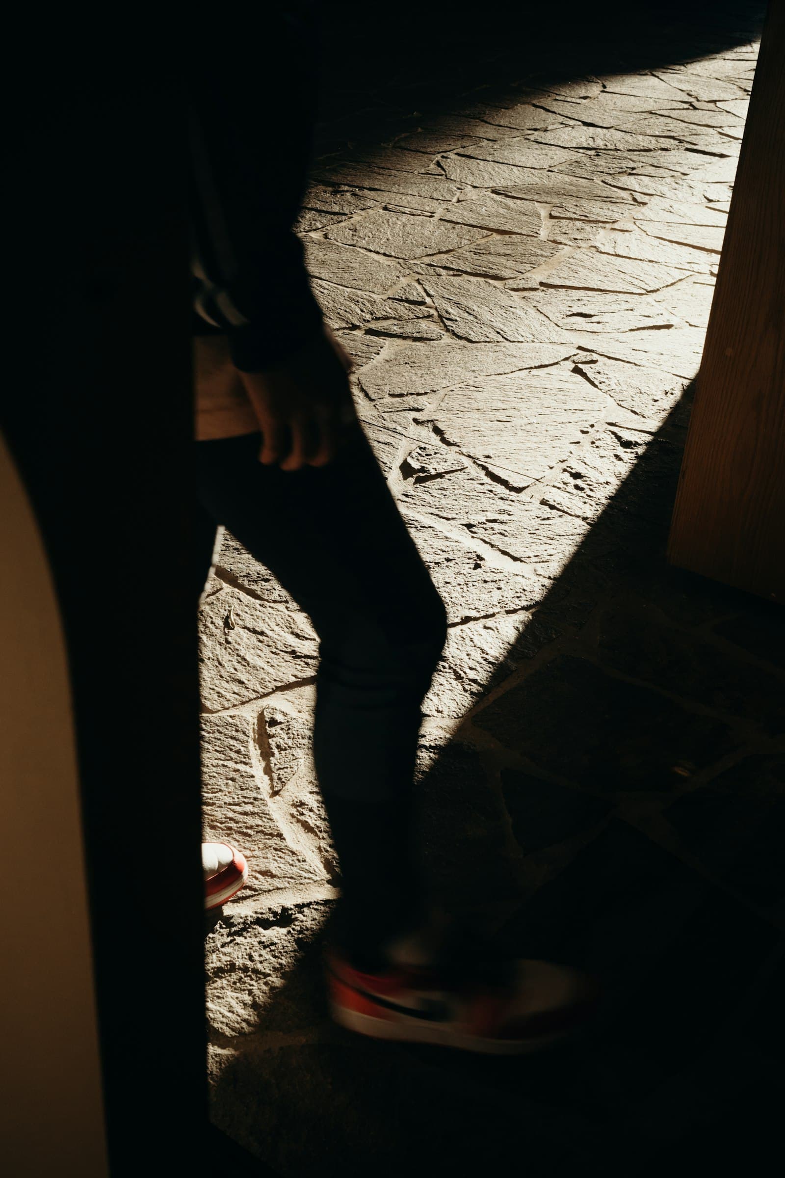 A person stepping out of a dark doorway into a band of warm light
