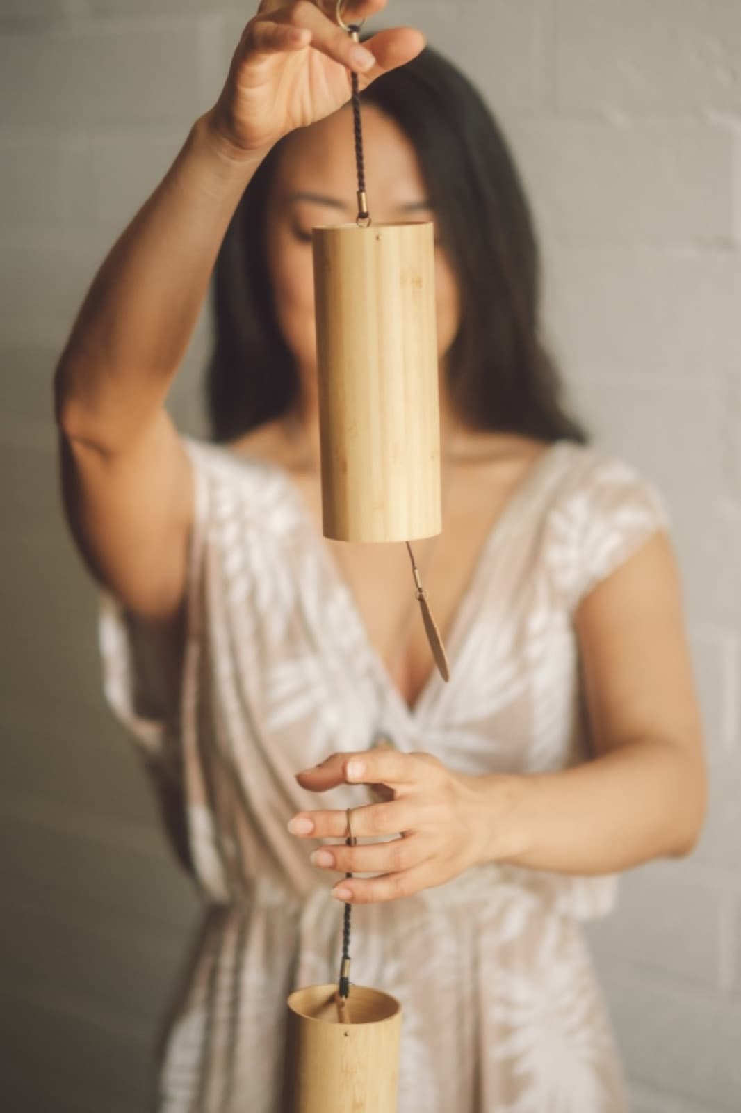 A bamboo chime held up in front of the face, hands framing it