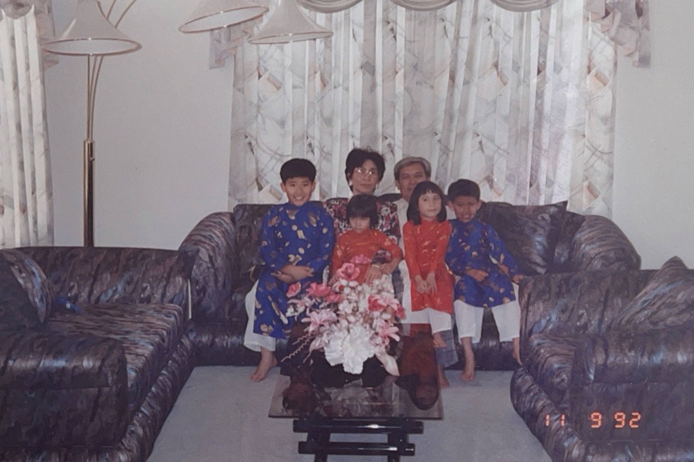 A family photograph from 1992, children in red áo dài in a living room